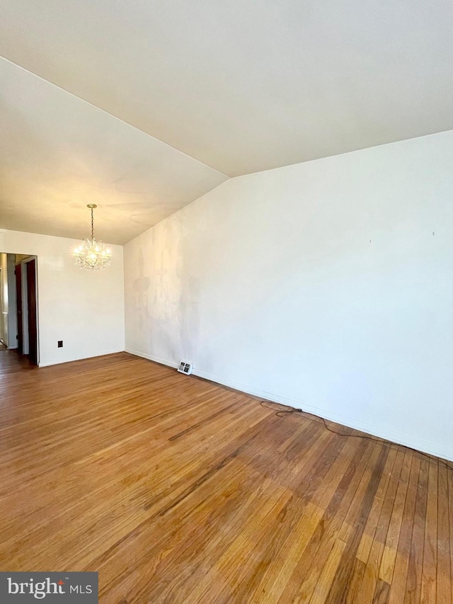 unfurnished room featuring vaulted ceiling, wood-type flooring, visible vents, and a notable chandelier