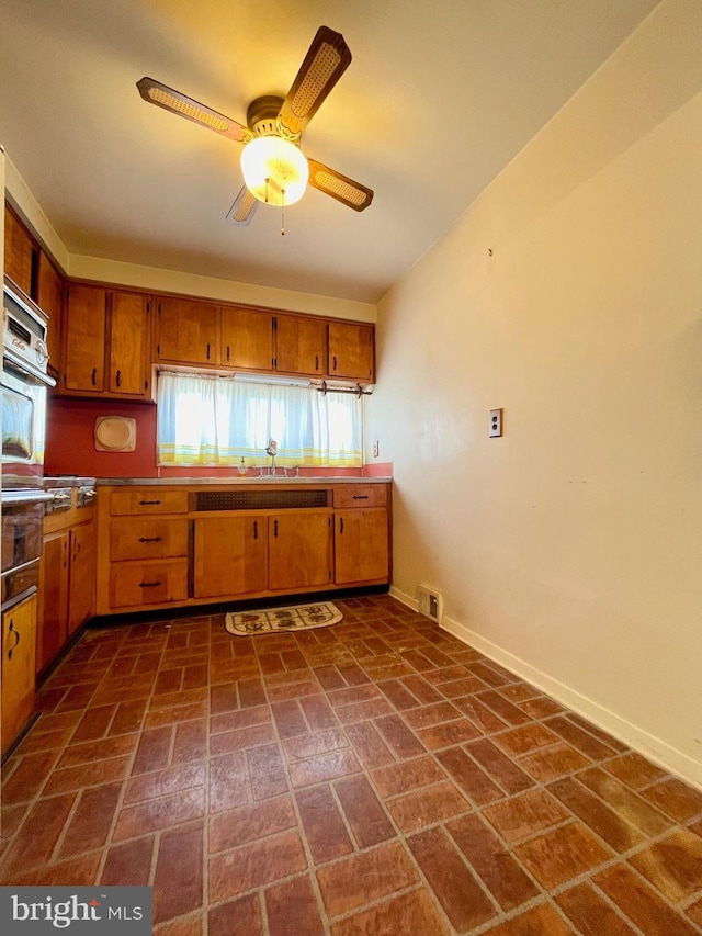 kitchen with visible vents, brown cabinetry, oven, and baseboards