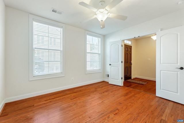 empty room with baseboards, a ceiling fan, visible vents, and light wood-style floors