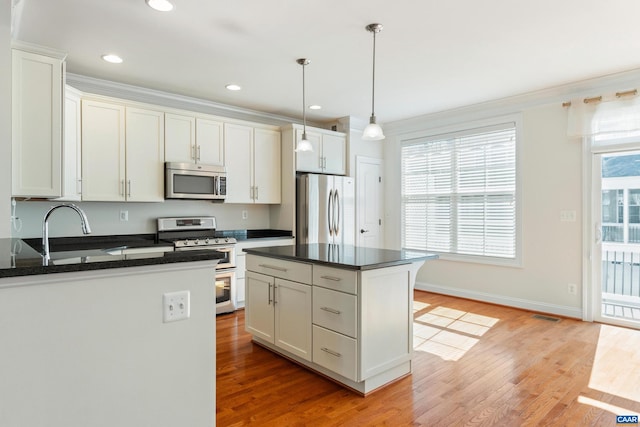 kitchen featuring visible vents, appliances with stainless steel finishes, ornamental molding, hanging light fixtures, and light wood-style floors