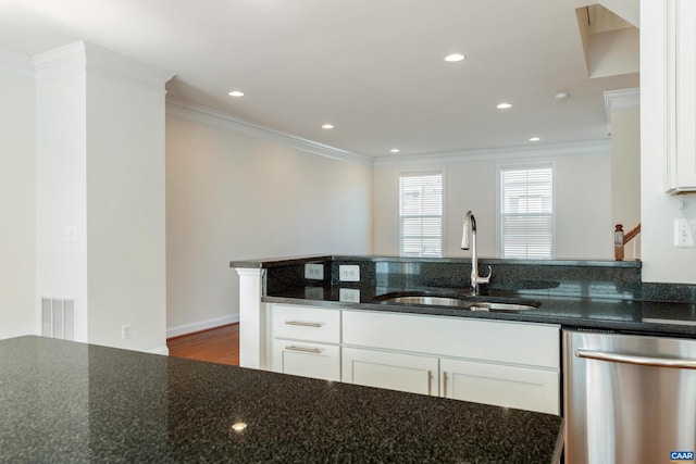 kitchen featuring stainless steel dishwasher, ornamental molding, white cabinetry, a sink, and dark stone countertops