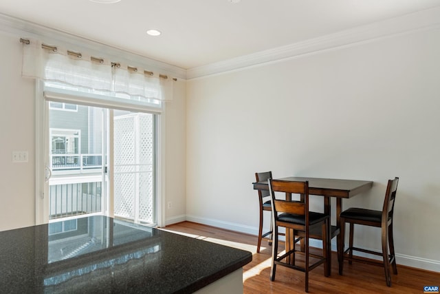 dining room featuring crown molding, baseboards, wood finished floors, and recessed lighting