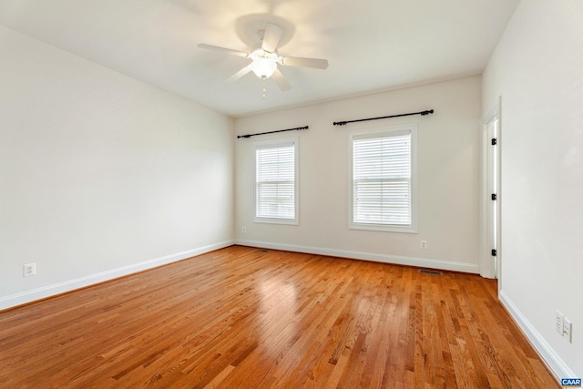 empty room with a ceiling fan, light wood-type flooring, and baseboards