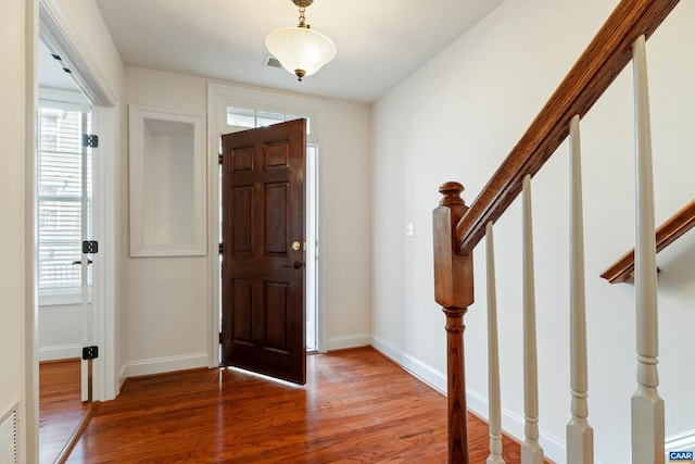 foyer with stairway, baseboards, and wood finished floors