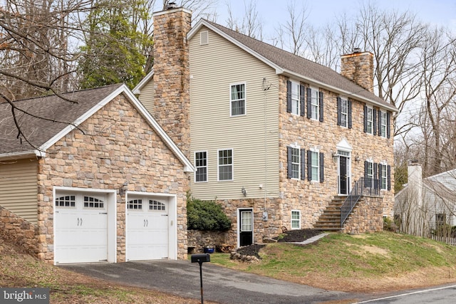 53 S Main St, Stockton, NJ 08559 - view of home's exterior with stone siding, aphalt driveway, a chimney, an attached garage, and roof with shingles
