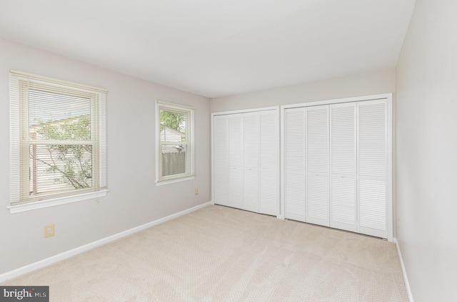 unfurnished bedroom featuring carpet flooring, two closets, and baseboards