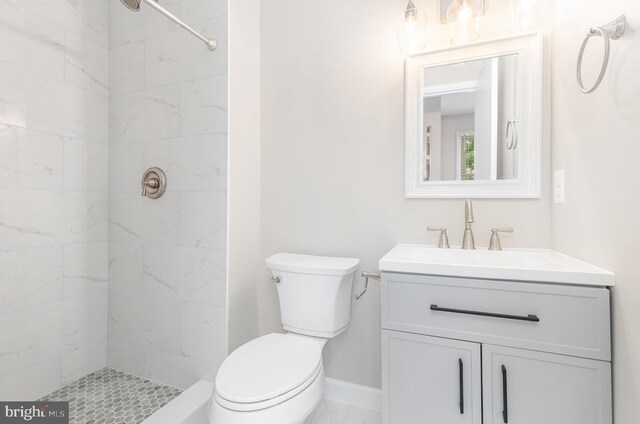 full bath featuring a tile shower, vanity, and toilet