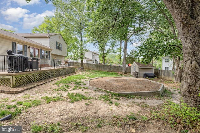 fenced backyard featuring a shed, an outdoor structure, and a wooden deck