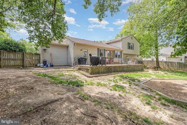 rear view of property featuring a deck, an attached garage, and a fenced backyard