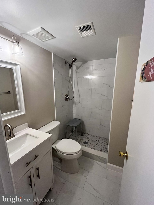 full bath with visible vents, toilet, marble finish floor, a tile shower, and vanity