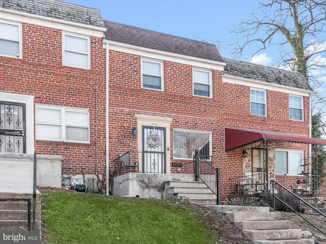 townhome / multi-family property featuring a high end roof, mansard roof, and brick siding