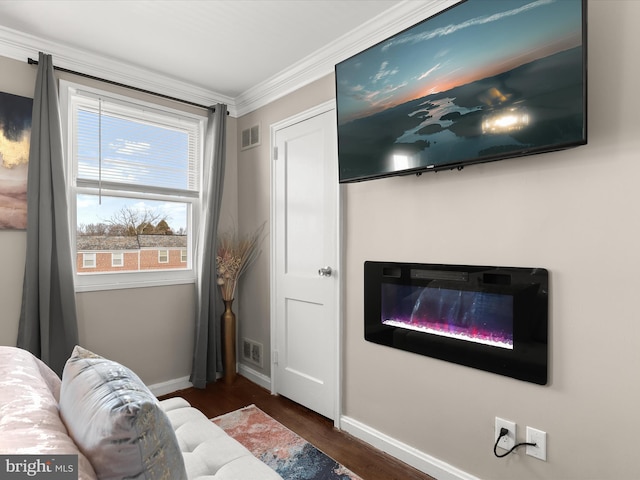 living room featuring dark wood-style flooring, crown molding, visible vents, a glass covered fireplace, and baseboards