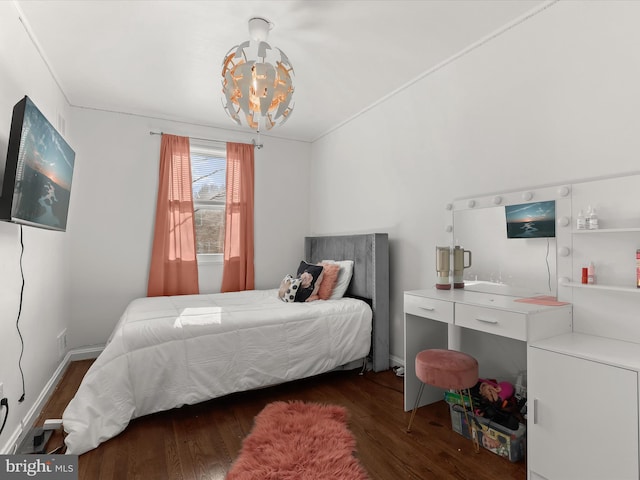 bedroom featuring an inviting chandelier, baseboards, and wood finished floors