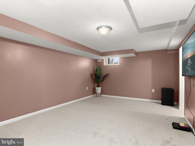 below grade area with a textured ceiling, carpet flooring, and baseboards