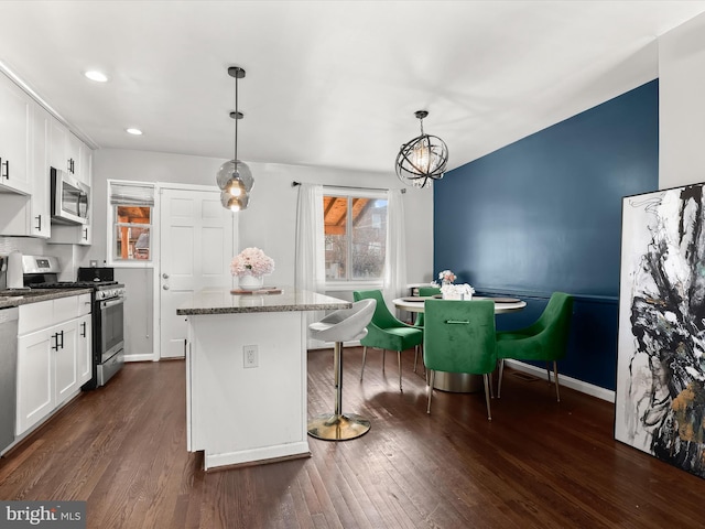 kitchen with a kitchen island, white cabinetry, stainless steel appliances, and dark wood-type flooring