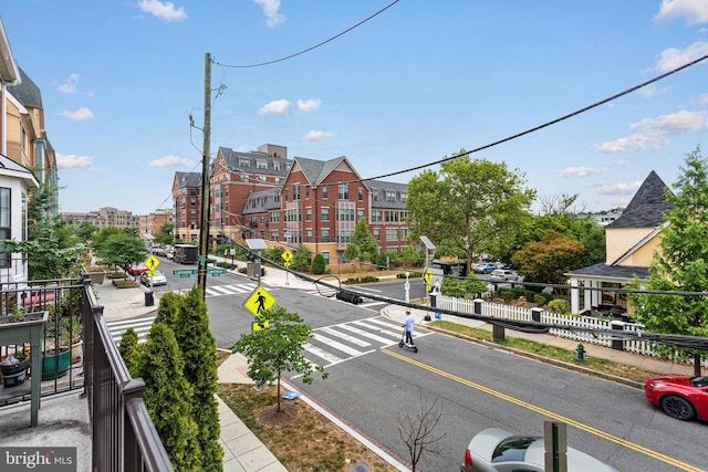 view of road featuring curbs, street lighting, traffic signs, and sidewalks