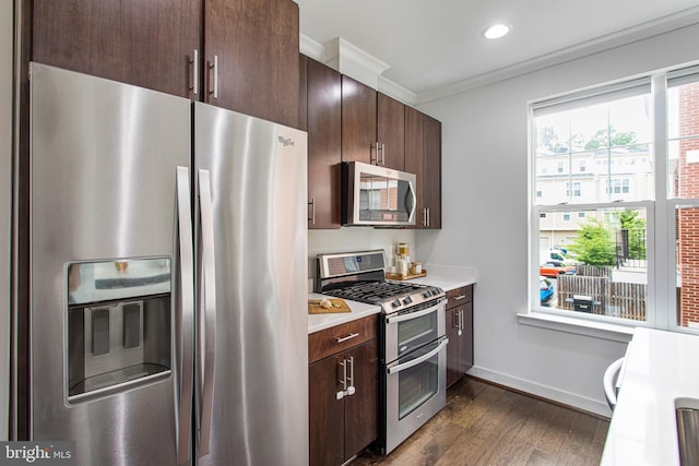 kitchen with stainless steel appliances, light countertops, crown molding, and dark brown cabinets