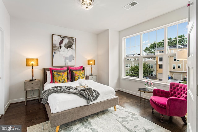 bedroom featuring baseboards, visible vents, hardwood / wood-style floors, and multiple windows