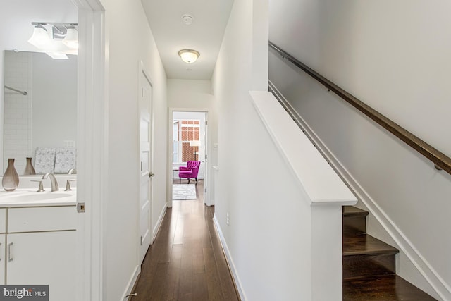 hallway featuring dark wood-type flooring, stairway, a sink, and baseboards