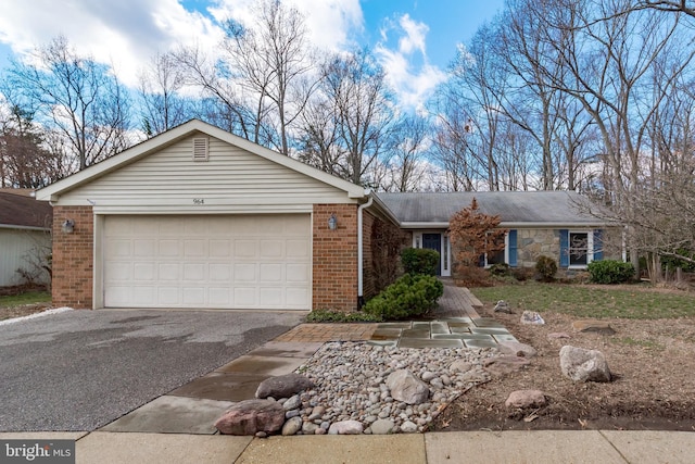 ranch-style house featuring an attached garage, aphalt driveway, and brick siding