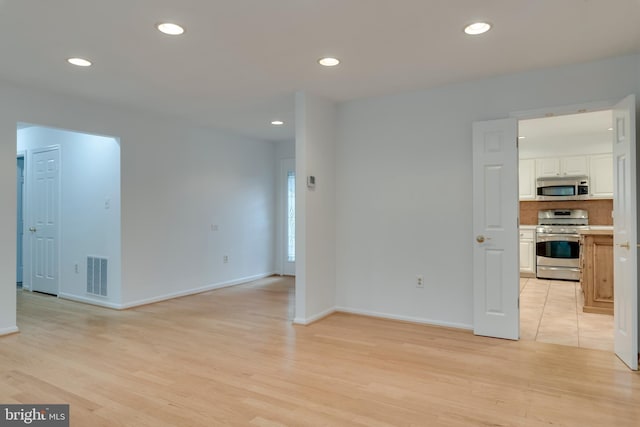 spare room featuring light wood-type flooring, recessed lighting, and visible vents