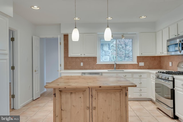 kitchen featuring light tile patterned floors, appliances with stainless steel finishes, wooden counters, and a center island