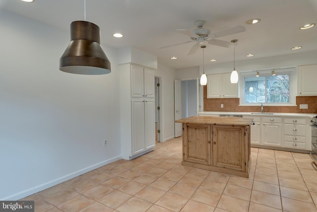 kitchen featuring a center island, light tile patterned floors, decorative backsplash, white cabinetry, and a sink