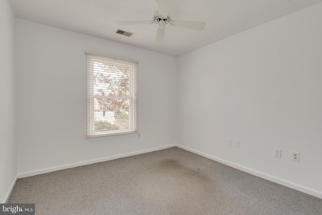 carpeted spare room with ceiling fan, visible vents, and baseboards