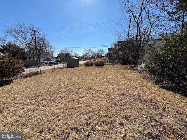 view of yard featuring an outbuilding, fence, and a shed