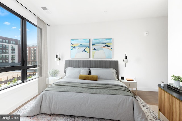 bedroom featuring multiple windows, visible vents, baseboards, and wood finished floors