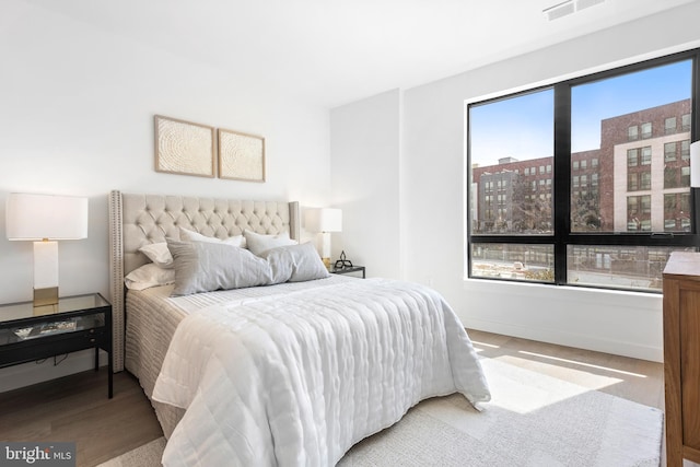 bedroom featuring wood finished floors, visible vents, and baseboards