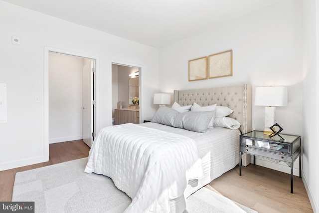 bedroom featuring ensuite bathroom, wood finished floors, and baseboards