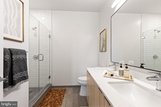 bathroom featuring toilet, a shower stall, double vanity, and a sink