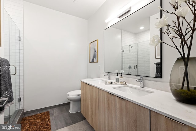 full bath featuring a sink, a shower stall, toilet, and double vanity