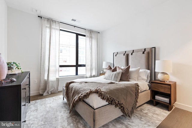 bedroom featuring light wood-type flooring, visible vents, and baseboards