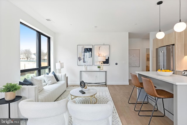 living room with light wood finished floors, visible vents, and baseboards