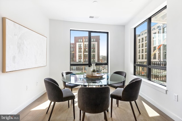 dining area with a city view, wood finished floors, visible vents, and baseboards