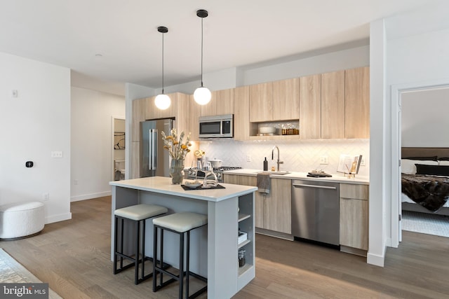 kitchen featuring modern cabinets, appliances with stainless steel finishes, light brown cabinetry, a kitchen bar, and open shelves