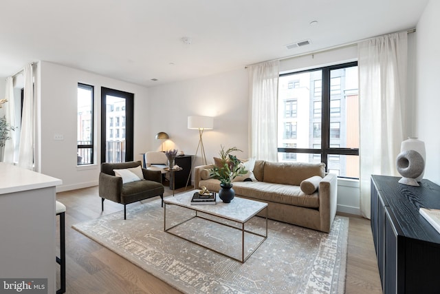 living area with light wood-style flooring, visible vents, and baseboards