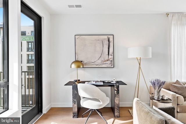 office area with visible vents, baseboards, and wood finished floors