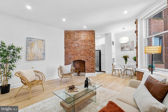 living area featuring light wood-type flooring, a fireplace, baseboards, and recessed lighting