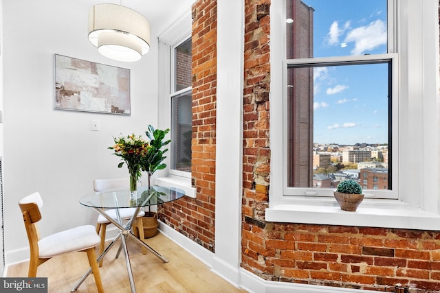 interior space featuring brick wall, wood finished floors, and baseboards