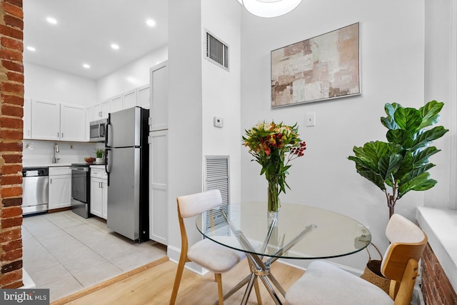 dining area with light wood finished floors, visible vents, and recessed lighting