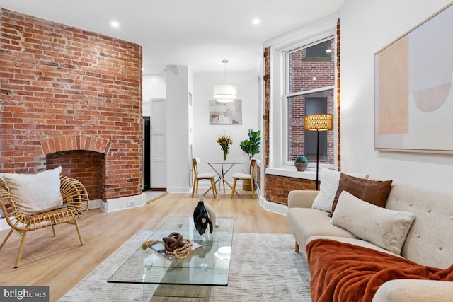 living room featuring light wood-style flooring, a fireplace, baseboards, and recessed lighting