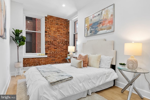 bedroom featuring brick wall, baseboards, and wood finished floors