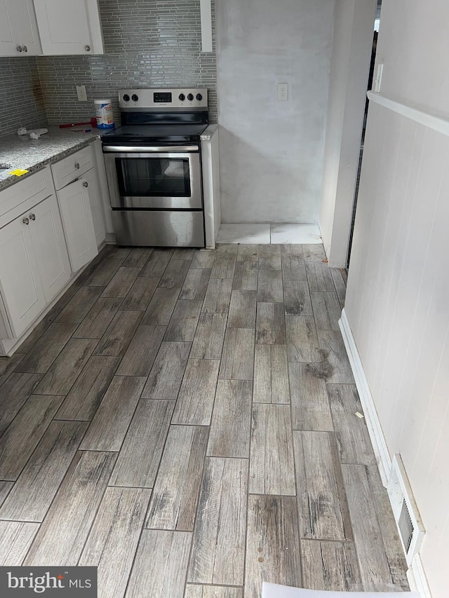 kitchen with wood finish floors, visible vents, backsplash, and stainless steel electric stove