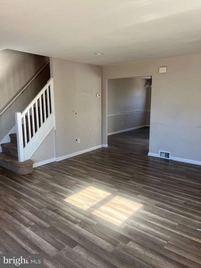 spare room featuring stairway, wood finished floors, visible vents, and baseboards