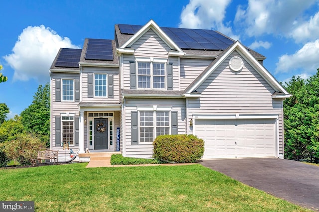 traditional-style house featuring driveway, an attached garage, roof mounted solar panels, and a front lawn