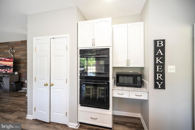 kitchen featuring dark wood-style flooring, white cabinets, black appliances, and light stone countertops