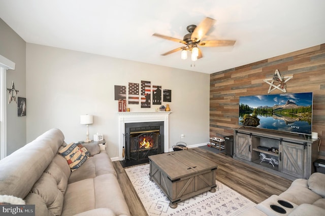 living area featuring wood walls, a lit fireplace, an accent wall, and light wood-style floors